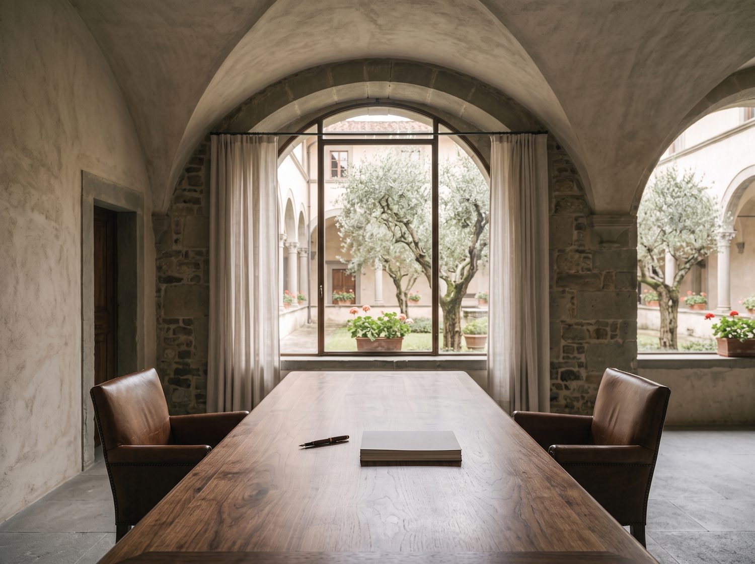 Una sala riunioni sotto le volte di un palazzo fiorentino: un lungo tavolo in noce, due poltrone una di fronte all'altra, una penna e dei documenti, la finestra sul chiostro.